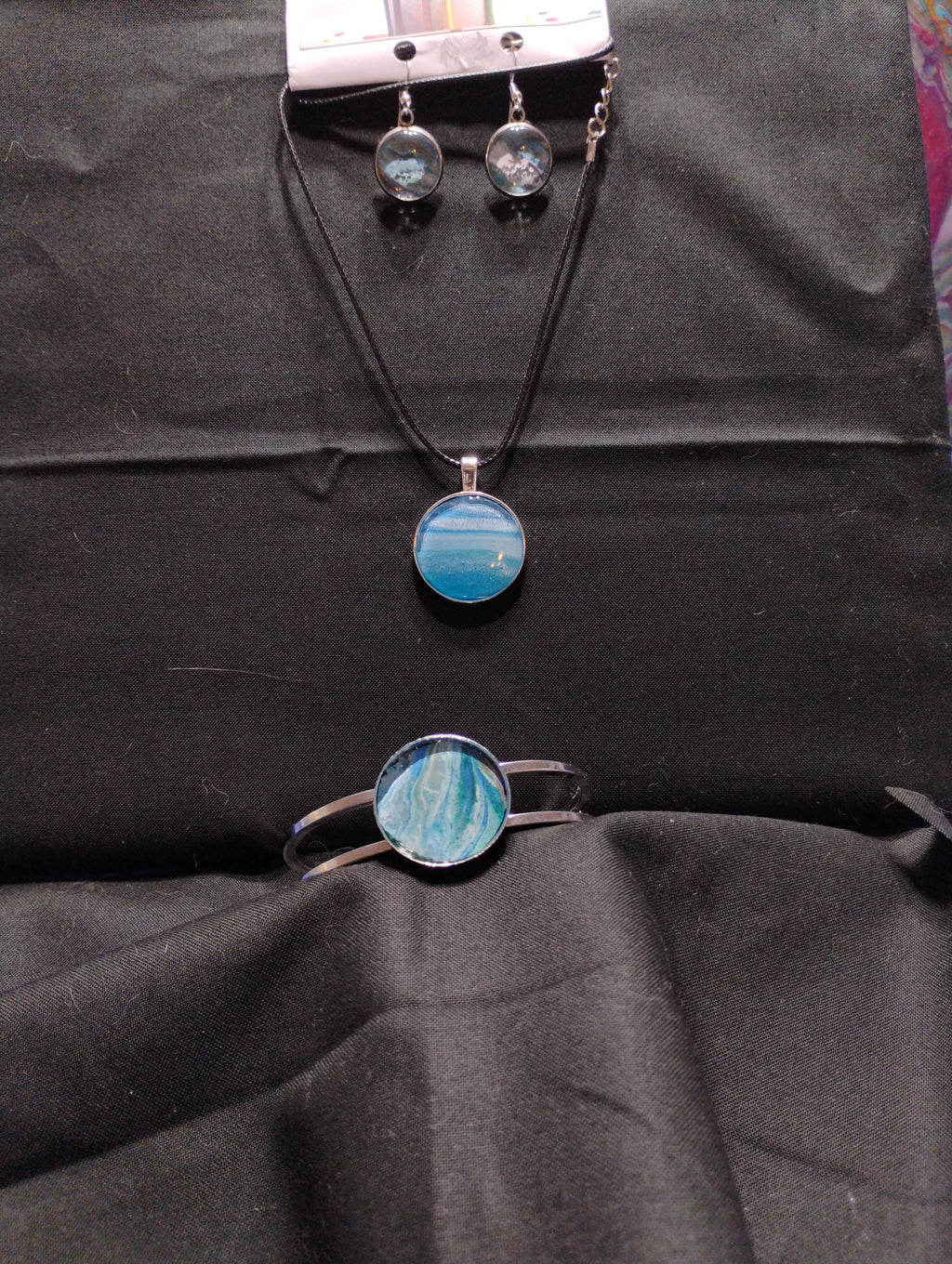 Jewelry set with blue circular pendants on a black fabric background