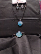 Jewelry set with blue circular pendants on a black fabric background